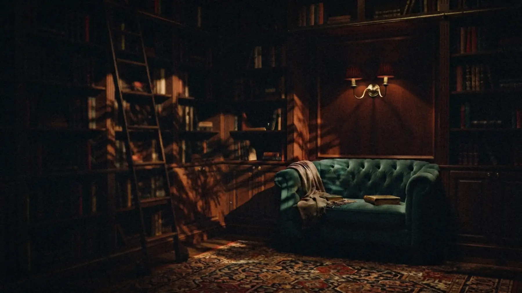 A teal velvet loveseat beneath a red-shaded brass sconce in a dark mahogany library